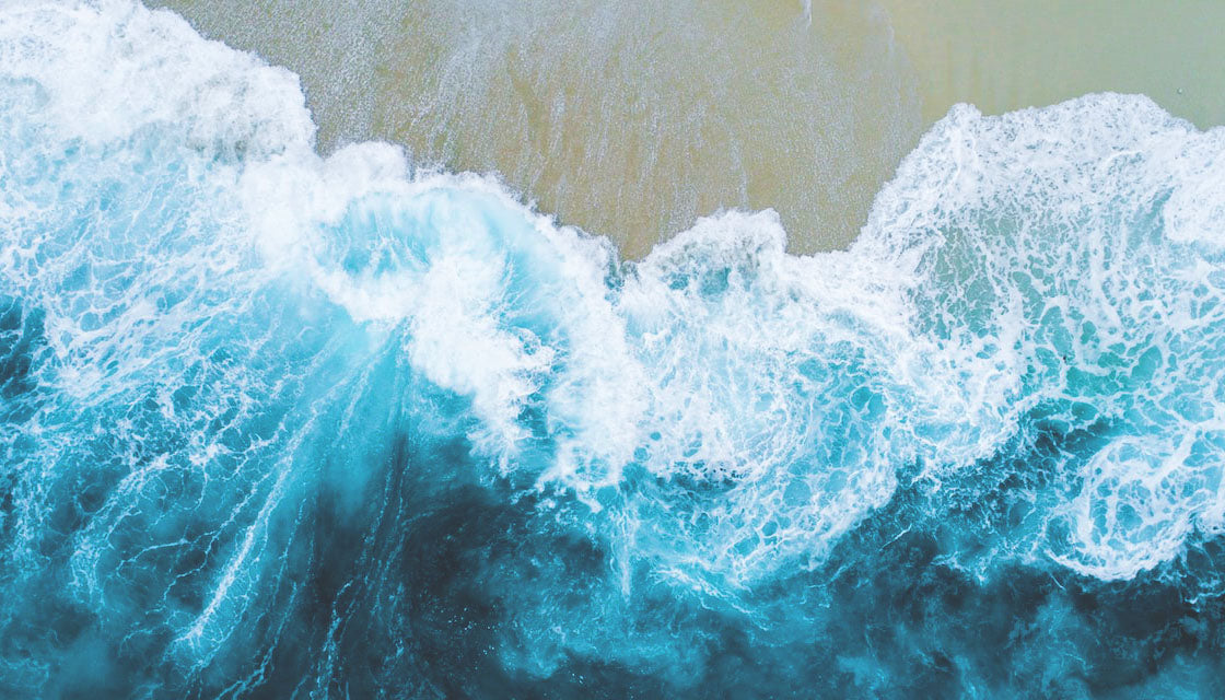Powerful waves hitting a beach causing swirls and foam