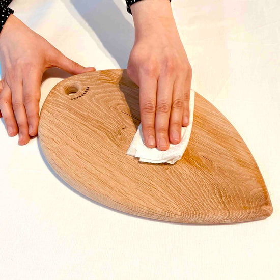 Hands cleaning an unprotected cutting board from dust and fat